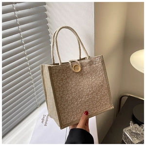 Detail of floral linen tote bag with woven handles and decorative wooden button closure