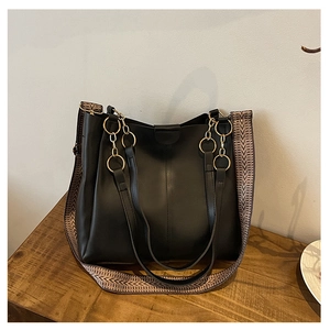 Detail of a large black tote bag with gold hardware and a vintage woven shoulder strap