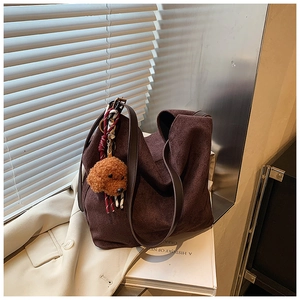 Gros plan d'un sac cabas en daim marron foncé avec un pendentif chien et lumière douce