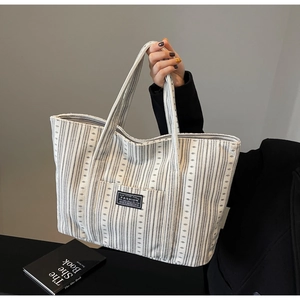 Détail du grand sac cabas en toile à rayures noires et blanches et écusson de mode