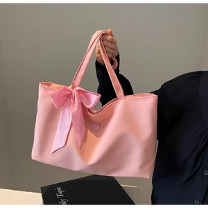 Detailansicht einer rosa Tragetasche mit großer karierter Schleife und rundem E-Anhänger