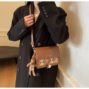 Detail of vintage brown crossbody bag with ethnic woven pattern and cute rabbit charm
