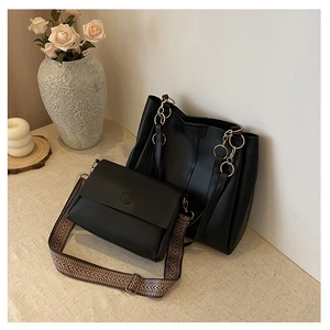 Detail of black tote bag with gold ring chain and crossbody bag with woven strap