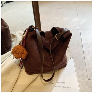 Détail du sac hobo en daim marron foncé avec un charmant pendentif chiot et une bandoulière