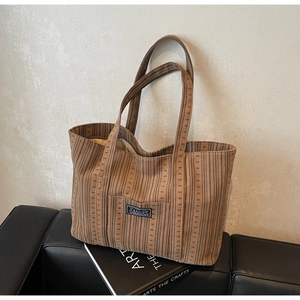 Gros plan d'un grand sac cabas en toile à rayures marron posé sur un canapé en cuir