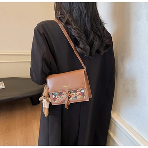 Detail of caramel leather crossbody bag with geometric weave and cute bear charm