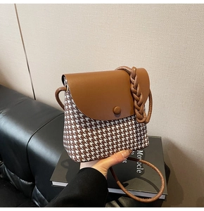 Detail of houndstooth bucket bag with leather braided handle and adjustable strap