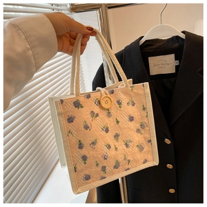 Detailed close-up of floral lace lunch bag featuring white rope handles and a wooden button