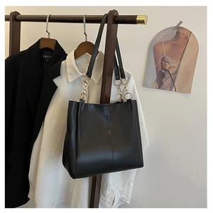 Detail of black matte leather tote bag with vertical stitching and gold chain straps