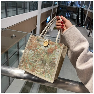 Close-up of linen tote bag with tapestry floral patterns and rustic wooden button closure