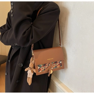 Brown leather crossbody bag with ethnic patterned flap and a cute rabbit doll pendant