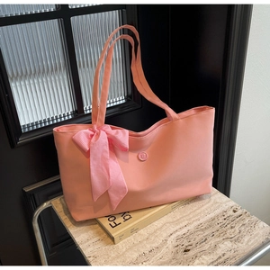 Rosa Tragetasche mit Gingham-Schleife und E-Buchstaben-Verschluss auf Steinfläche