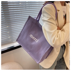 Dettaglio della borsa tote in tela viola con testo merci bianco e manici in corda spessa