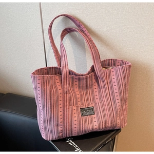 Détail du sac fourre-tout en toile à rayures roses avec poche frontale et étiquette