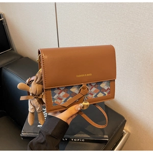 Detail view of brown vintage crossbody bag with geometric patchwork and rabbit charm