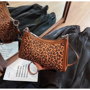 Dettaglio borsa a spalla leopardata con rifiniture in pelle marrone e zip metallica