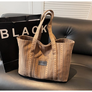 Détail du sac cabas marron en velours côtelé avec patch fashion sur canapé noir