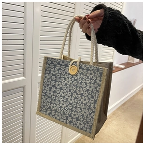 Close-up of small linen tote bag with blue floral prints and a decorative wooden button