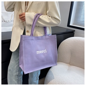 Dettaglio di una borsa tote in tela lavanda con stampa merci indossata da una modella