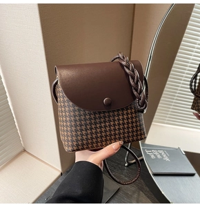 Detailed close-up of houndstooth fabric texture and leather flap on the bucket bag