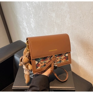 Detail of vintage brown leather bag featuring colorful woven fabric and a cute rabbit charm