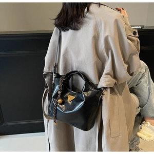 Detail der schwarzen Lackleder-Handtasche mit goldenen Beschlägen und Anhänger-Dekor
