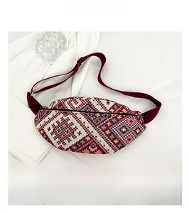 Détail d'un sac banane tissé ethnique avec motif géométrique et sangle rouge réglable