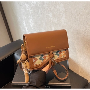 Brown leather crossbody bag with colorful woven pattern and cute rabbit charm detail