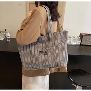 Détail du sac cabas gris à rayures verticales avec étiquette mode et toile de coton texturée