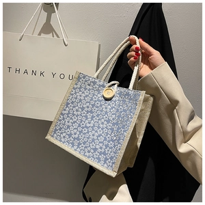 Detail of floral canvas lunch bag featuring button closure and twisted rope handles