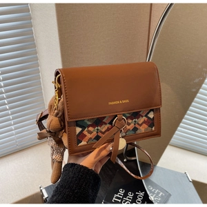 Detail of vintage brown crossbody bag with colorful woven pattern and plush bear charm