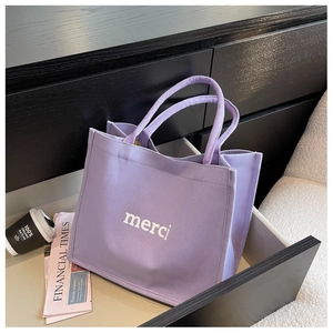 Dettaglio della borsa tote in tela viola con stampa merci in un cassetto di legno