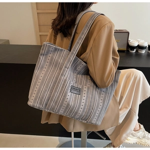 Gros plan d'un cabas en toile rayée grise avec étiquette noire dans un café cosy