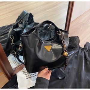 Detail der glänzenden schwarzen Handtasche mit LURADIA 1945 Emblem und Flechtanhänger