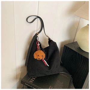 Détail du sac fourre-tout en toile noire avec bandoulière en cuir et breloque ourson