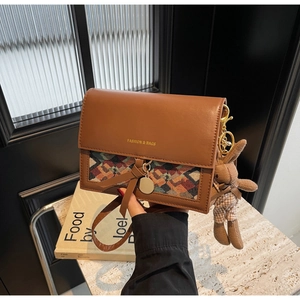Close-up of brown vintage leather crossbody bag with woven patterns and rabbit charm