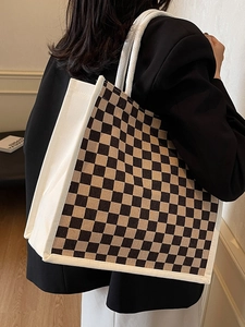 Detail of checkered canvas tote bag with woven rope handles and reinforced white piping