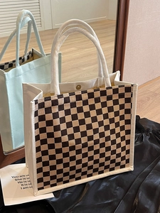 Detail of checkered canvas tote bag with thick woven rope handles and magnetic metal snap