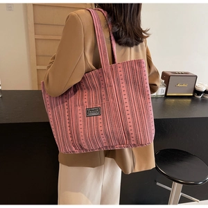 Détail du grand sac cabas tissé rose à rayures avec étiquette Fashion et anses robustes