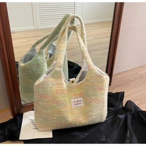 Detail of fuzzy knit tote bag featuring a metallic snap button and woven brand label