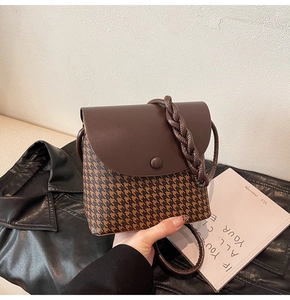 Detail of vintage houndstooth crossbody bag with brown leather flap and woven strap
