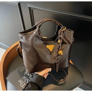 Detailaufnahme der dunkelbraunen Vintage-Umhängetasche mit Glanzeffekt und Anhänger