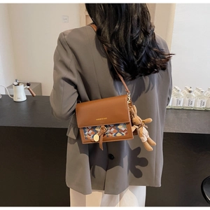 Detailed view of brown crossbody bag with geometric fabric pattern and cute bunny charm