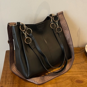 Black large tote bag in matte leather with golden ring handles and patterned strap