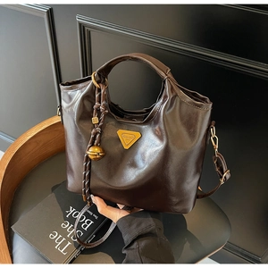 Detailansicht der dunkelbraunen glänzenden Ledertasche mit metallischem Dreieckslogo