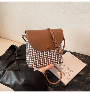 Detail of crossbody bag featuring houndstooth pattern and brown leather lid on jacket