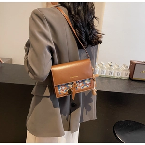 Retro shoulder bag with brown leather and colorful woven patterns worn with grey blazer