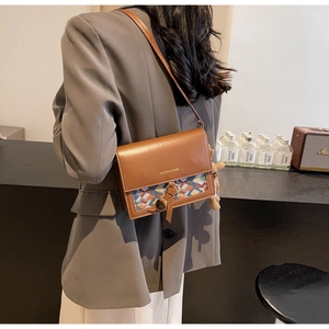 Rear view of a model wearing a brown crossbody bag with woven panel and bear charm