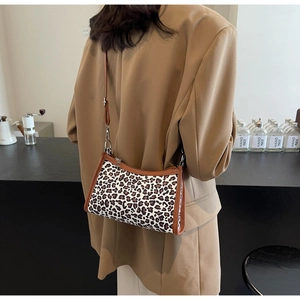 Borsa sottobraccio leopardata mostrata su una modella in un caffè urbano raffinato