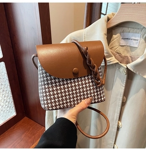 Detailed close-up of retro houndstooth pattern bag with leather flap and woven strap